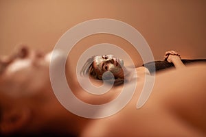 Woman with clay mask near blurred man in spa salon