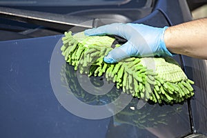 Woman clean car in glowes, sponge in hand