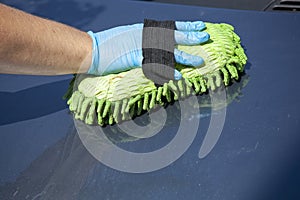 Woman clean car in glowes, sponge in hand