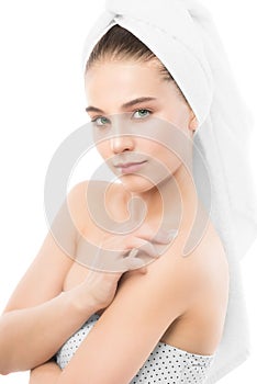 Woman with clean face and towel on her head applying moisturizer cream on shoulders. .