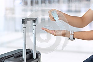 Woman clean hand by alcohol gel sanitizer after holding handle Luggage bag in airport, protection Coronavirus disease infection.