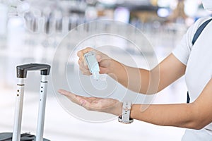 Woman clean hand by alcohol gel sanitizer after holding handle Luggage bag in airport, protection Coronavirus disease infection.