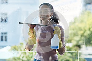 Woman cleaner, cleaning window and spray bottle with detergent, liquid soap and squeegee with housekeeping. Female