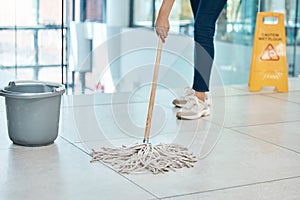 Woman cleaner mop floor at office, with water in plastic bucket and put sign as warning or caution for staff. Employee