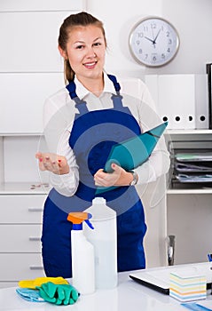 Woman cleaner is signing documents while cleaning