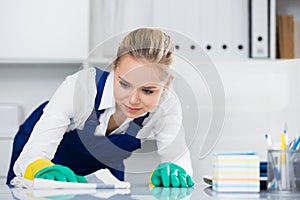 Woman cleaner wiping desk in office