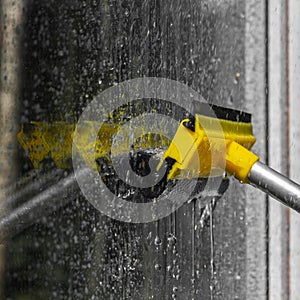 woman cleaner wiping window glass with a telescopic MOP outside a suburban private home, close-up, window washing concept with wat