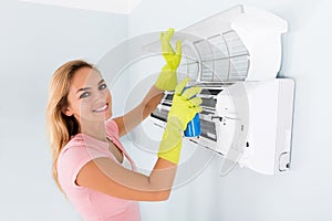 Woman Cleaning The Air Conditioner