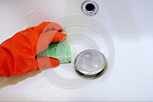 woman cleaning a bathroom\'s sink with sponge, Person cleaning the kitchen sink with a gloves