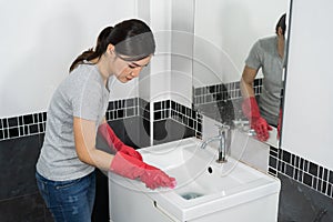 Woman cleaning bathroom sink with brush