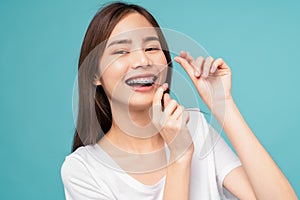 woman cleaning braces on teeth with dental floss on blue background, Concept oral hygiene and health care.