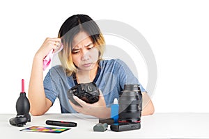 Woman cleaning a camera with cloth and photography equipment on table.