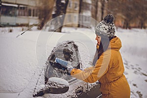 Woman cleaning car windshield of snow