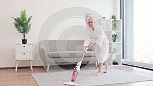 Woman cleaning carpet in living room with cordless vacuum