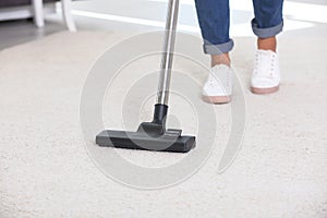 Woman cleaning carpet with vacuum cleaner,