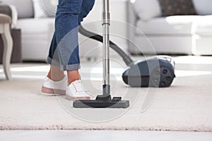 Woman cleaning carpet with vacuum cleaner