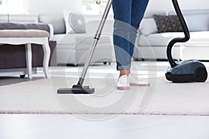 Woman cleaning carpet with vacuum cleaner