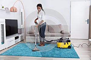 Woman Cleaning Carpet With Vacuum Cleaner