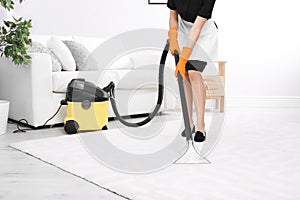 Woman cleaning carpet with vacuum cleaner