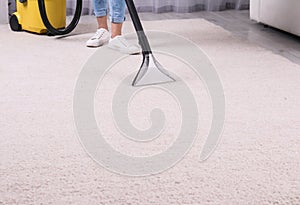 Woman cleaning carpet with vacuum cleaner, closeup