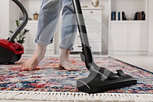 Woman cleaning carpet with vacuum cleaner at home, closeup. Space for text