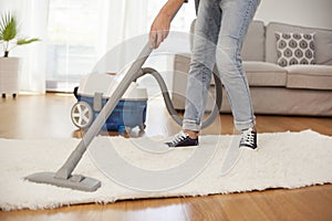 Woman cleaning carpet with a vacuum cleaner in room