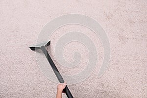 Woman cleaning carpet with vacuum cleaner, top view.