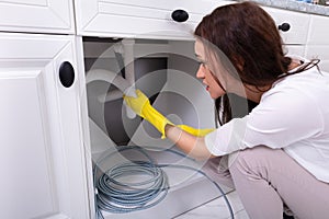 Woman Cleaning Clogged Sink Pipe