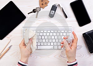 Woman cleaning a computer keyboard with an antiseptic spray photo