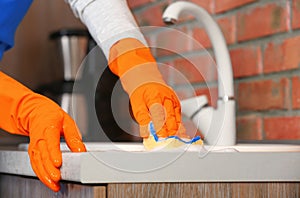 Woman cleaning counter with sponge in kitchen