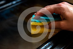 Woman cleaning dirty and greasy oven with stove in kitchen