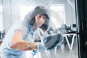 Woman cleaning dirty window by using towel. View through the glass