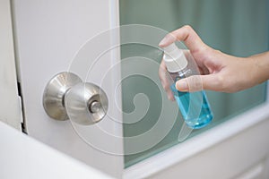 Woman is cleaning door handle with alcohol spray
