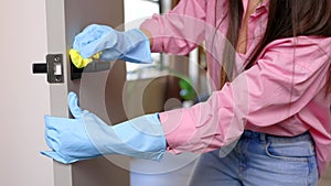 Woman cleaning door handle with antiseptic at home. Concept cleaning at home