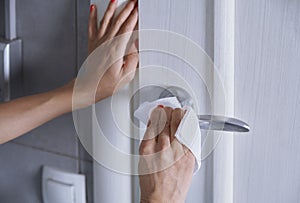 Woman cleaning the door handle with disinfecting wipe