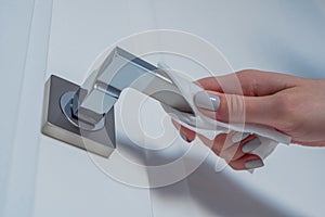 Woman cleaning door handle with wet wipe - disinfection concept - close up