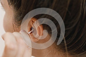 Woman cleaning ear with a cotton swab