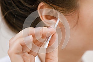 Woman cleaning ear with a cotton swab