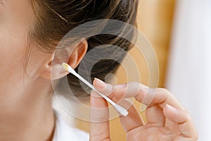 Woman cleaning ear with a cotton swab