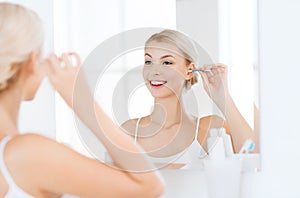 Woman cleaning ear with cotton swab at bathroom