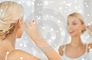 Woman cleaning ear with cotton swab at bathroom