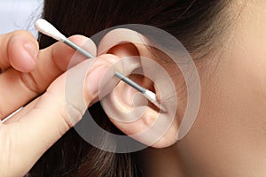 Woman cleaning ear with cotton swab, closeup