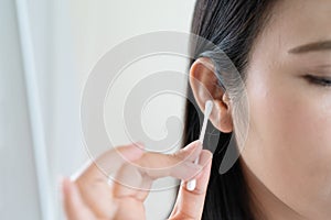 Woman cleaning ear with cotton swab. Healthcare and ear cleaning concept