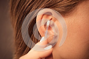 Woman cleaning ear with cotton swabs closeup