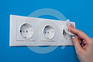 Woman cleaning electrical outlet, socket with wet wipe - close up view