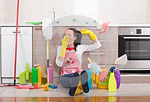 Woman with cleaning equipment and products on kitchen floor