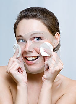 Woman cleaning face by cotton pad