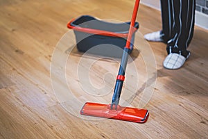 Woman cleaning floor of living room by mob.