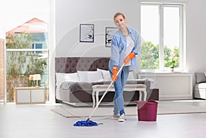 Woman cleaning floor with mop in bedroom