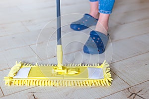 Woman cleaning floor with yellow mop at home. Microfiber mop isolated on white wooden floor background, closeup, indoors
